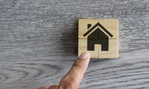 Icon of a home with a wooden background and a hand pointing.