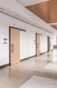 A hallway with three exam rooms and three doors open and closed.