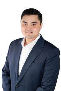 Professional headshot of HFO Investment Real Estate partner Jack Stephens, a man with short black hair, wearing a navy blue suit jacket and a white dress shirt, smiling slightly against a white background.